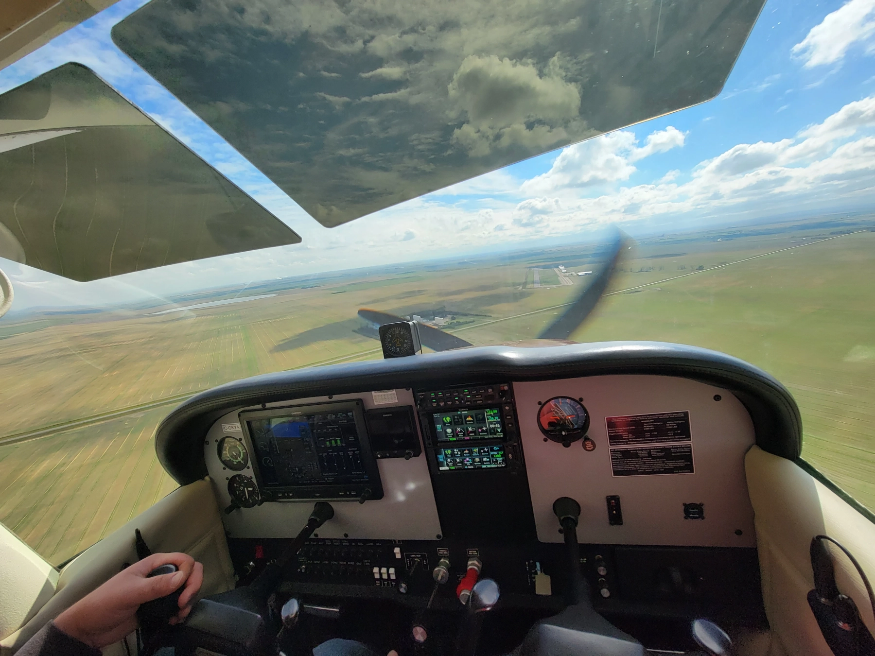 Several small private airplanes are parked in a row on an airport tarmac under a clear blue sky